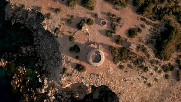 Overhead view of pirate lookout tower in Ibiza during sunset. Aerial view rotating downwards.