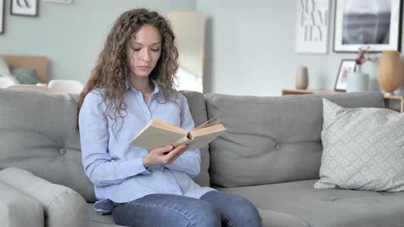 Curly Hair Woman Reading Book while Sitting on Couch