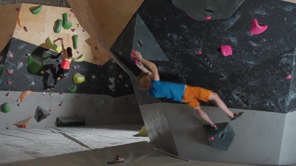 Young Climbers Training on a Climbing Wall Man and Female Practicing Rockclimbing and Moving Up