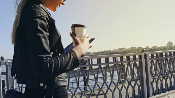 Young Professional Woman Walking Across a Pedestrian Walkway with Her Tablet and Cup of Coffee