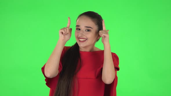 Portrait of Pretty Young Woman Is Pointing Up Fingers. Green Screen