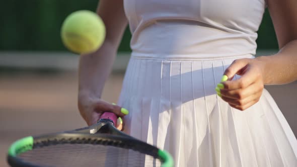 Female Tennis Player Bounces Ball on Racquet Closeup