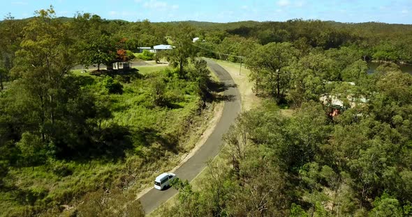 Campervan going up the hill in green scenery of eucalyptus trees.