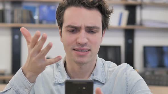 Portrait of Creative Man Reacting To Loss While Using Smartphone