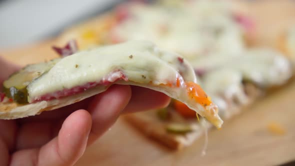 Hand Takes a Slice of Sliced Pizza with Mozzarella Cheese Tomatoes Pepper