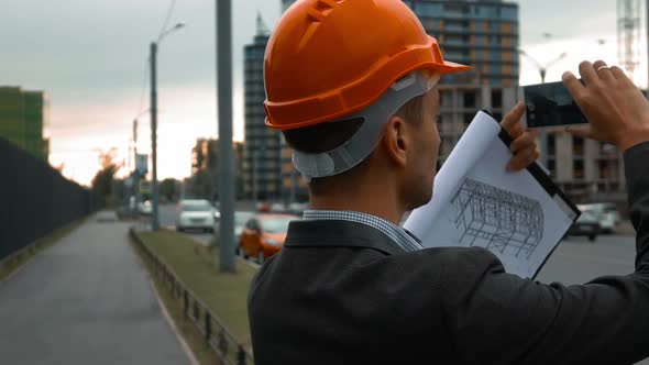 Engineer with the Smart Phone Taking Pictures of Construction