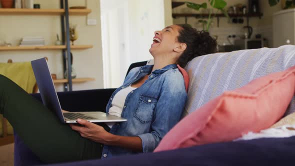 Smiling caucasian woman using laptop on video call, sitting on sofa at home