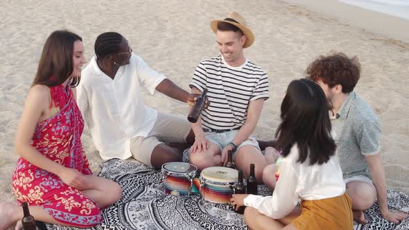 Group of Cheerful Multiethnic Young People on the Beach Toasting with Beer