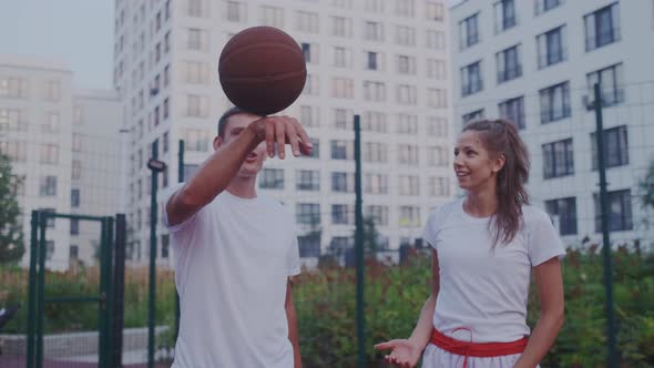 Young People Have Fun on Sport Court. Man Show Off His Skill of Ball Spinning. Happy Girl Catch