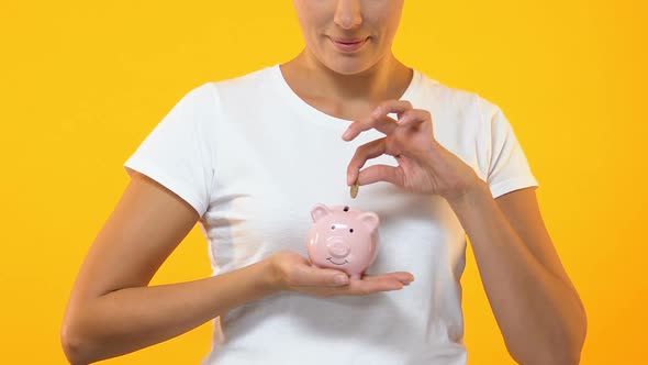 Smiling Woman Putting Coin in Piggy Bank, Budget, Savings for Future Investment