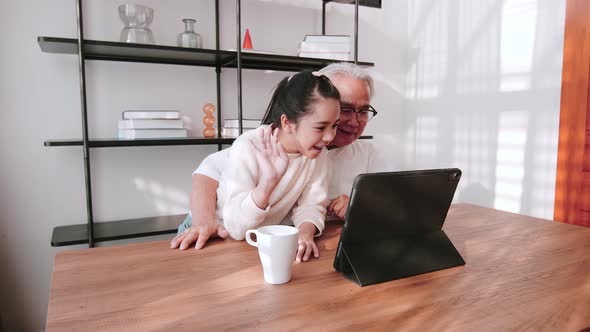 Senior Asian man with his granddaughter making video call with family members. Video call concept.