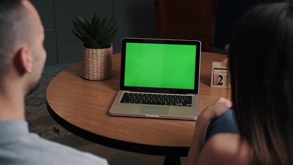 Young Man and Woman at Home Office Business Using Green Mock-up Screen Laptop Computer While Sitting