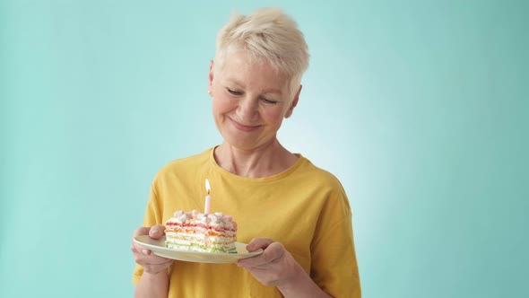 Senior Woman Blowing out Candle on B-day Cake