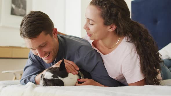 Caucasian couple playing with dog in bad at home