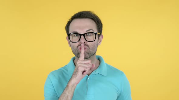 Man Gesturing Silence Finger on Lips Yellow Background