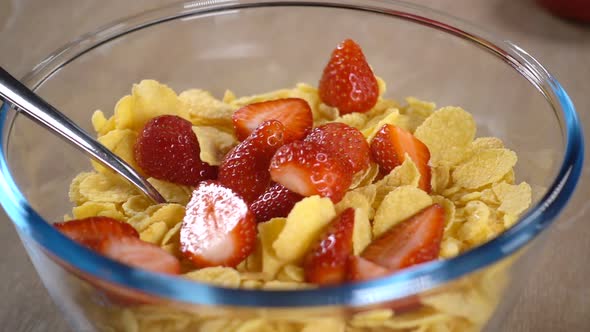 Sliced Strawberries Fall Into a Bowl with Cornflakes