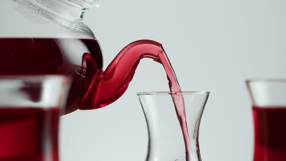 Pouring Red Fruit Tea in Armudu Glass on White Background