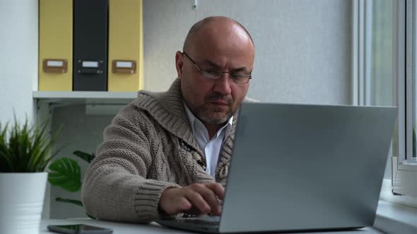 Serious Businessman Working on Laptop Computer at Home Office