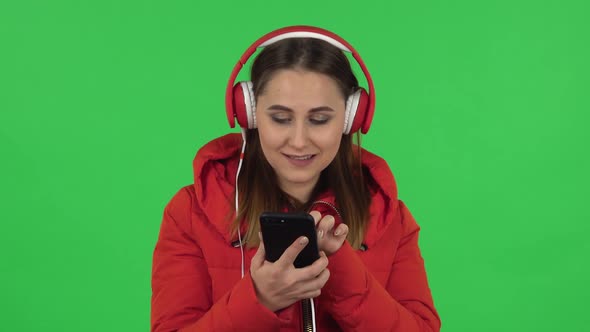 Portrait of Lovely Girl with Mobile Phone Is Dancing and Enjoying Music in Big Red Headphones. Green