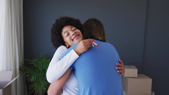 Happy mixed race couple holding house keys hugging each other at new apartment house