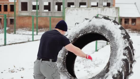 Sportsman Lifting a Large Rubber Tyre in the Winter, Doing Crossfit Exercises