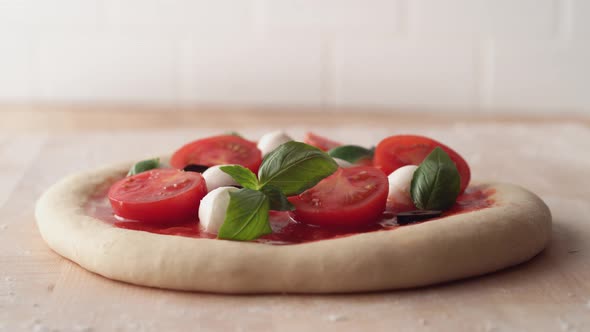 Camera follows putting sliced black olives on a pizza dough. Slow Motion.