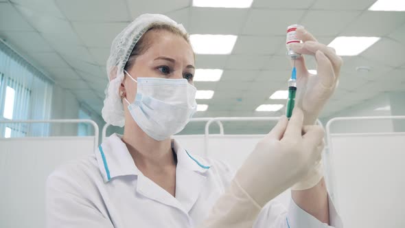 Doctor in a Face Mask is Filling a Syringe