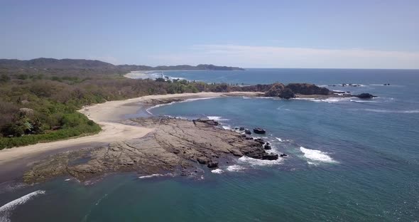 Aerial drone view of the beach, rocks and tide pools in Playa Palada, Guiones, Nosara, Costa Rica.