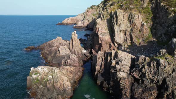 Cinematic slow flying aerial view of coast with cliffs, waves and ocean, Kullaberg Sweden