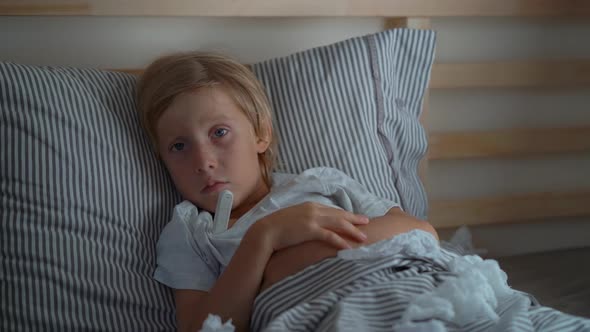 Superslowmotion Shot of a Sick Little Boy with a Thermometer in a Bed