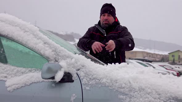 Man cleaning car windshield from snow and ice