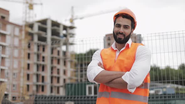 Portrait of Smiling Architect Man Standing on the Construction Site with Crossed Hands Looking at