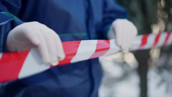 Female Hands in Gloves Hanging Warning Tape at Crime Scene on Winter Day Outdoors