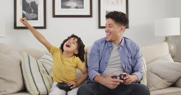 Happy biracial man and his son playing video games