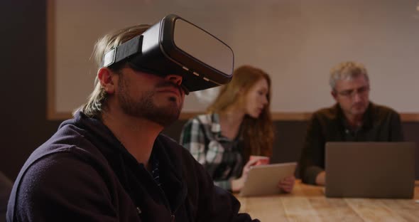 Man wearing VR headset with colleagues working in creative office