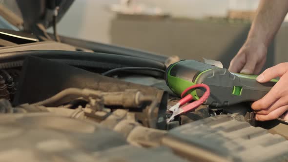 Auto service worker checking voltage on car battery. Service engineer working in car service station