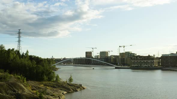 Aerial, low, drone shot towards a boat driving under the Isoisansilta bridge, between Mustikkamaa is