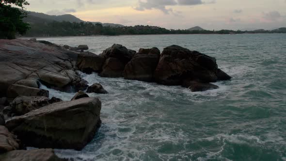 Waves crashing into rocky shoreline at the beach in Chaweng Noi, Koh Samui, Thailand