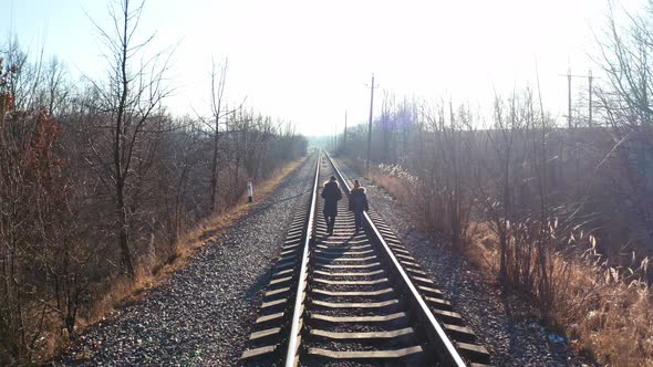 People walking on railway in forest. Traveler people walking along the railroad tracks