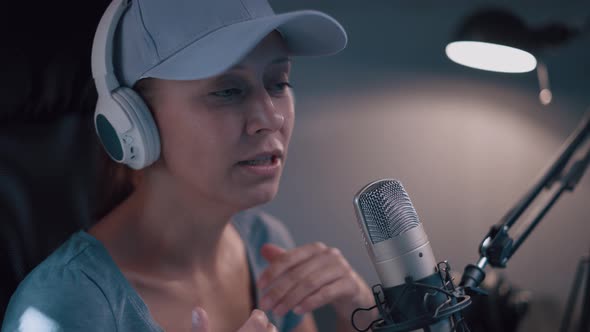 Beautiful Woman In A Cap And White Headphones Leads A Live Stream