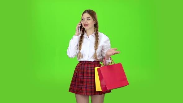 Schoolgirl Speaks on the Phone and Holds Shopping Bags. Green Screen. Slow Motion