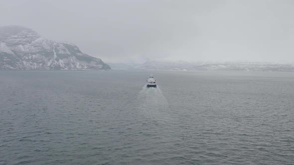 Ferry sailing in Northern Norway on a winter cloudy day, aerial view