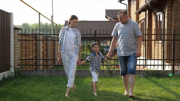 Father and Pretty Mother Hold Happy Little Boy Hands