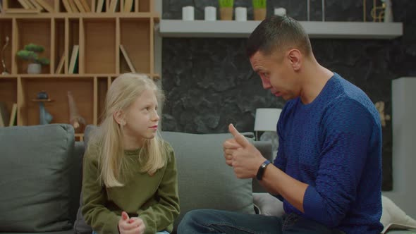 Adorable School Age Girl with Hearing Loss and Deaf Father Bonding on Couch