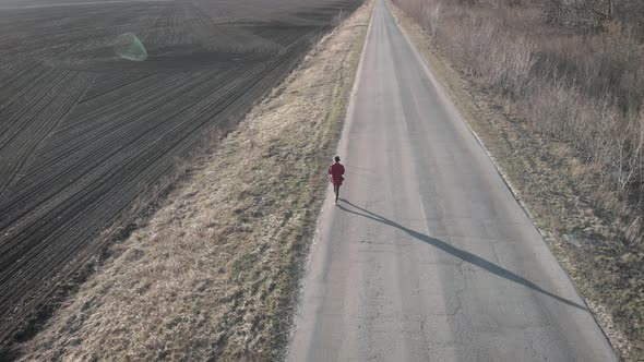 Aerial View of Woman Farmer with Digital Tablet Computer Looks at a Fresh Plowed Field After Winter