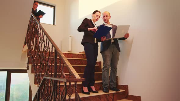 Executive Manager Holding Laptop Talking with Businesswoman