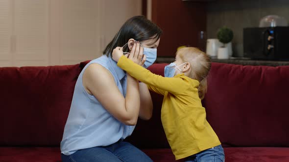 Little Daughter Puts on Sick Mother Protective Medical Mask at Home. Coronavirus Quarantine Lockdown