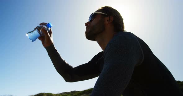 Triathlete man pouring water on his face on a sunny day