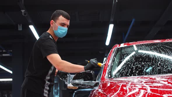 Auto Detailing  Man Applying a Cleaning Foam on a Car with a Small Brush