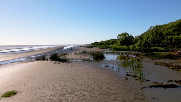 Low level aerial drone forward flying capturing the unique riverbanks sand texture, sandy tidal flat